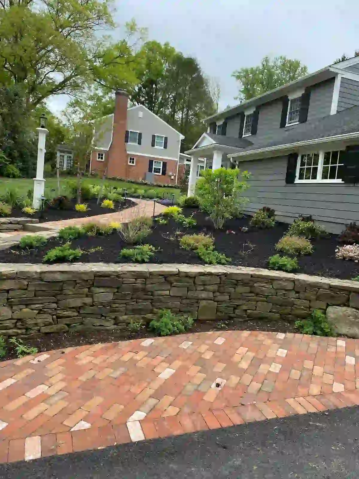 Brick walkway and stone retaining wall designed and installed to elevate the home’s front-yard landscape structure.